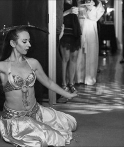 Erin McGurk balancing a curved sword on her head while seated in a dance pose